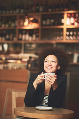 Mixed race, African American woman drinking coffee in cafe