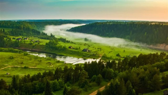 Fields and pine forest landscape at summer. Aerial view of misty foggy forest and the sunset at the evening time. Filmed on drone cinema camera. Ecology and nature forest concept.