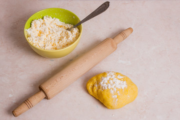 Rolling pin and yellow dough with white flour and green bowl wit