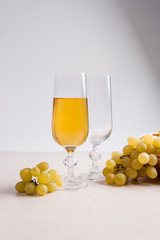 White wine and grapes. White wine in glass and grapes on light m