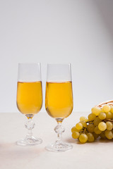 White wine and grapes. White wine in glasses and grapes on light