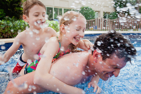 Father with children having fun in swimming pool.