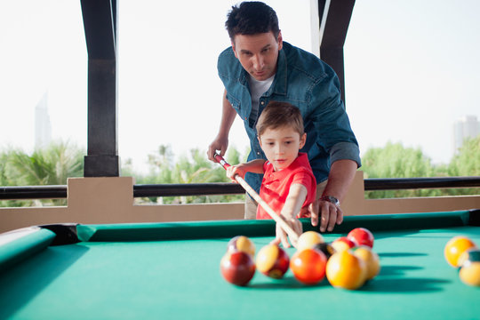 Father teaching his son billiard.
