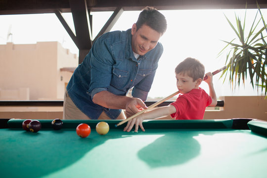 Father teaching his son billiard.