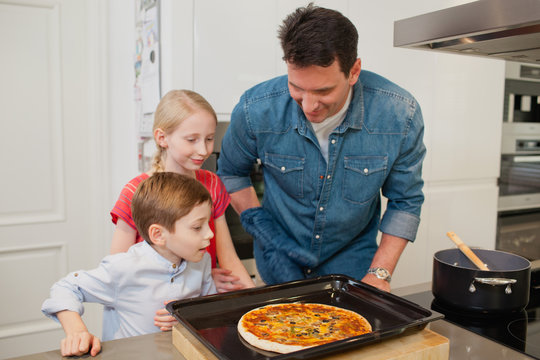 Father with children making pizza at kitchen.