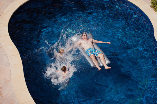 Father with children having fun in swimming pool.
