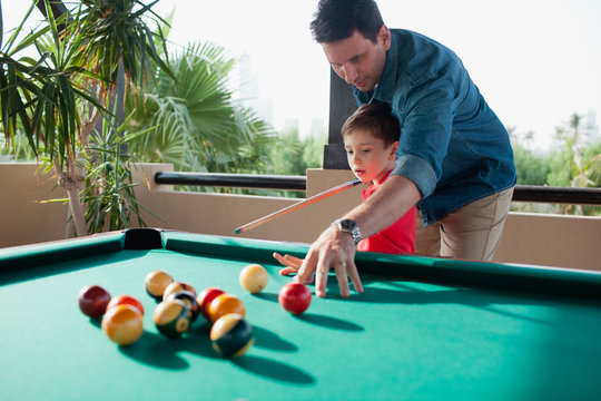 Father teaching his son billiard.