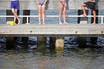 happiness - group of  faceless young people standing on pier and having sunbathe