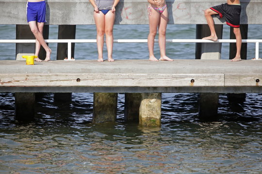 happiness - group of  faceless young people standing on pier and having sunbathe
