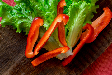Salad of fresh vegetables. Red pepper and green salad on dark wooden background. Vegetarian food.