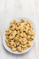 cashew on white dish on wooden background