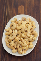 cashew on white dish on wooden background