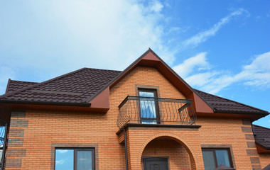 Building brick house construction with different types of attic  roof design and metal balcony