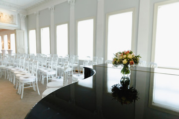 bouquet on a piano white chairs in a row