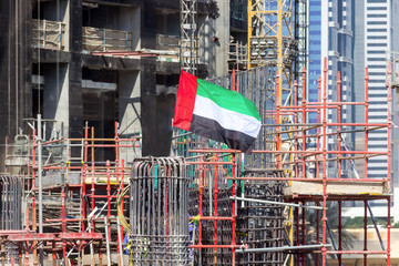 Construction site of a skyscraper. Flag of United Arab Emirates.