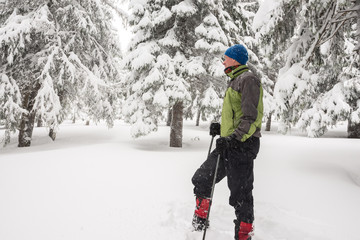 Fototapeta na wymiar Traveler resting, standing among the snow-covered pine trees