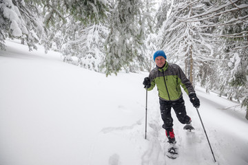 Fototapeta na wymiar Joyful traveler running snowshoeing in deep snow