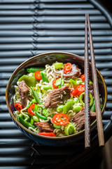 Hot asian noodle in dark bowl with chopsticks