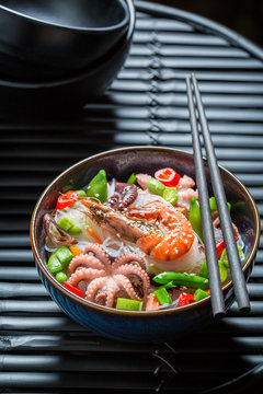 Enjoy your seafood noodle in dark bowl with chopsticks