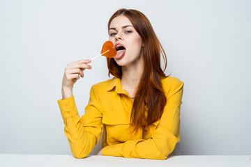 Fototapeta premium woman with sweet candy on a stick, yellow shirt