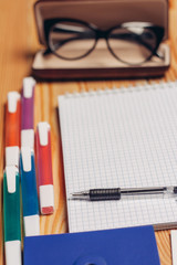 Case for glasses and colorful markers on the table, notebook with pen