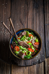 Delicious asian noodle in dark bowl with chopsticks