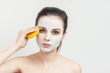 a woman wipes a mask from her face with a yellow sponge