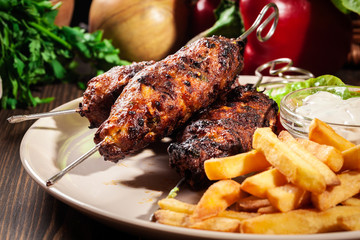 Grilled shish kebab served with fried chips and salad