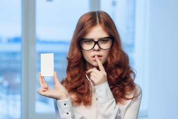 Fototapeta premium red-haired woman and badge in her hand, index finger near the lips
