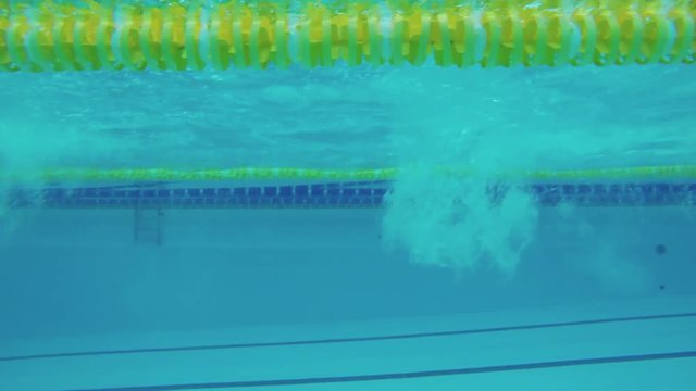 Female swimmer swims in pool 4k video. Underwater view from the water of crawl freestyle training of professional athlete.