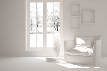 White room with armchair and winter landscape in window. Scandinavian interior design