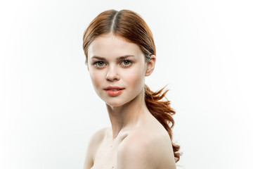 Fototapeta premium red-haired woman on a light background looks at the camera