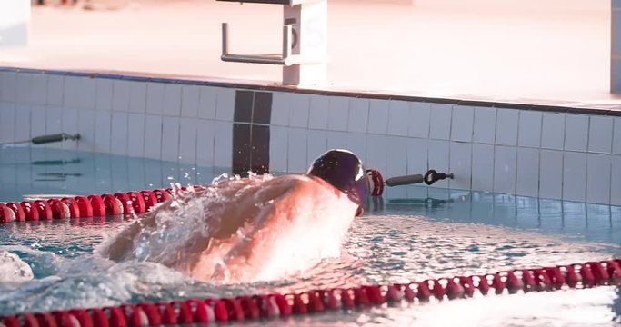 Male swimmer swims in pool HD slow-motion video. Finish butterfly training of professional athlete. Water splashing.