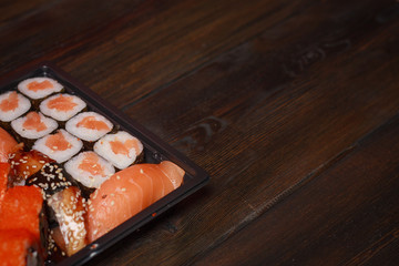 sushi and rolls in a special vessel for eating, wooden background
