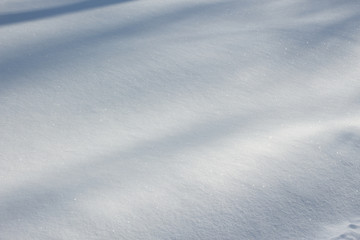 Fototapeta premium Fresh snow texture with natural shadows on winter ground. Horizontal color image of beautiful white nature background of snowy clean surface.