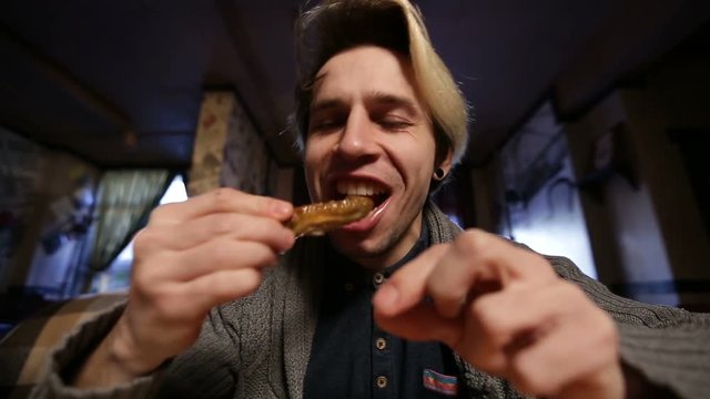 Young man eating tasty grilled chicken wing