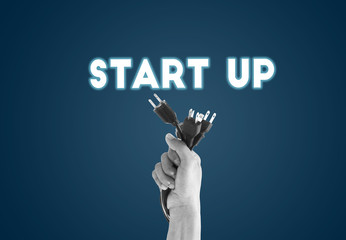 Businessman hand holding plug with Start up wording on interface screen. new business concept.