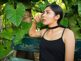 Asian woman sitting on the wooden chair in the garden