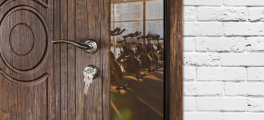Entrance to gym in fitness club, opened door with exercise bikes