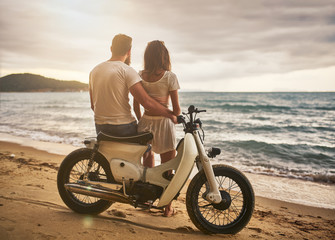 Fototapeta na wymiar romantic couple sitting on vintage bike watching sunset at koh samui thailand