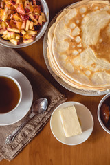 Stack of delicious homemade pancakes or blini with chocolate, cup of tea, butter