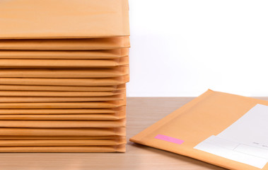 Stack of bubble wrap padded mailing envelopes on white background color over wooden table. Envelope packaging shockproof stack concept.