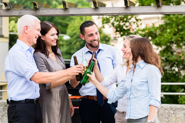 Büro Kollegen stoßen am Feierabend auf der Terrasse mit Bier an und feiern