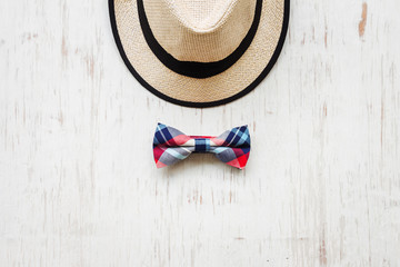 Men's accessories with brown hat and plaid bow tie on rustic wooden background 