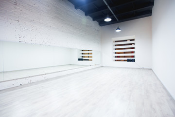 Interior of an empty dance and fitness studio with loft design and big mirrors.