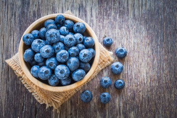 Blueberries in wooden bowl on wooden table background