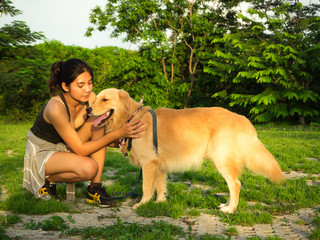 Golden retriever and Asian woman are playing in the park