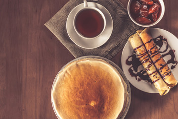 Stack of delicious homemade pancakes or blini with chocolate, cup of tea and jam