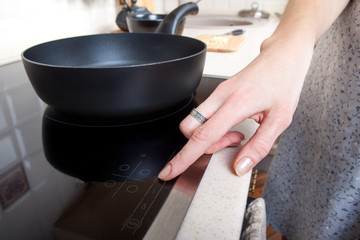 Fototapeta na wymiar Woman hand includes induction stove