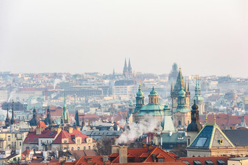 A view on the Prague roofs and street in the sunset through the fog